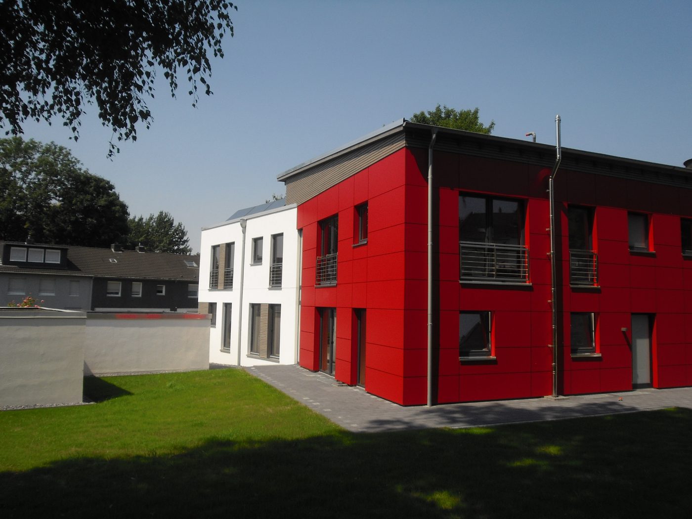 Mehrfamilienhaus in Rot und Weiß mit Garten
